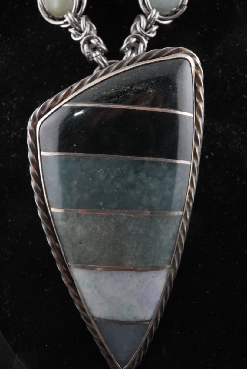 Strata of Still Water — Jade intarsia.  A layered composition of five distinct jades, shifting from deep green to pale mist, evokes a quiet landscape shaped by time. Fine silver inlays divide each stratum like geological memory, while the twisted frame echoes the slow forces of nature. More than ornament, it feels like a fragment of stillness—calm, grounded, and enduring.